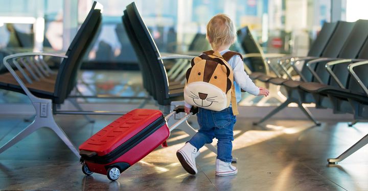 Child at the airport with suitcase and lion backpack 