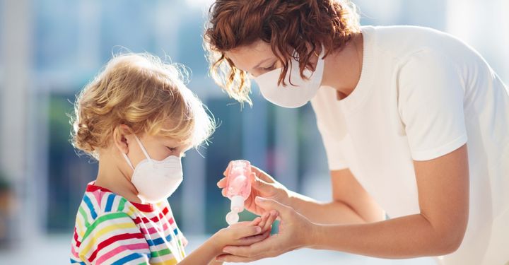 mother giving hand sanitiser to young son